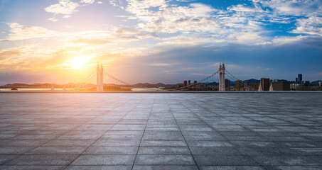Empty square floor and bridge with urban skyline at sunset in Zhoushan, Zhejiang, China.