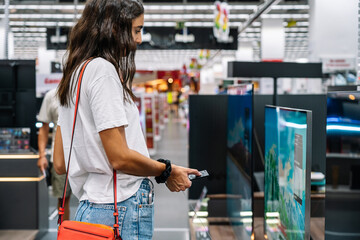 Focused woman choosing a tv in a tech store