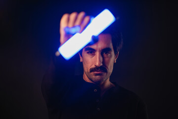 Man holding neon light in darkness