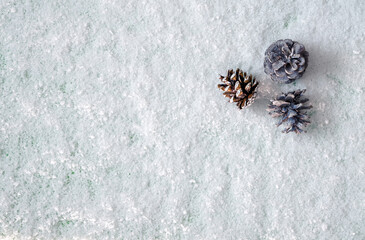 three pine cones on white snow, top view, space for text, background for various Christmas designs