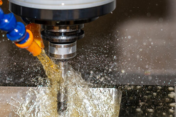 Close-up scene the CNC milling machine cutting the  mold parts with oil coolant method.