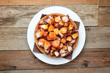 top view of a plate of octopus with olive oil and paprika, isolated on a wooden table
