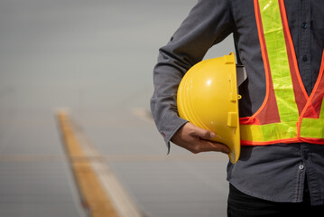 Engineer holding yellow hard hat for worker safety on blank background - obrazy, fototapety, plakaty