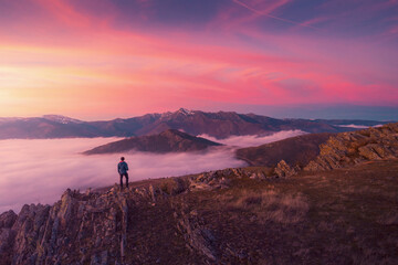 Lonely tourist on high summit of mountains in sunset