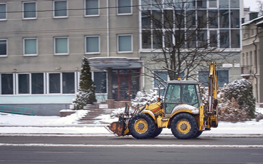 Backhoe loader driven on city street at winter day, motion drive. Loader with backhoe drive trough...