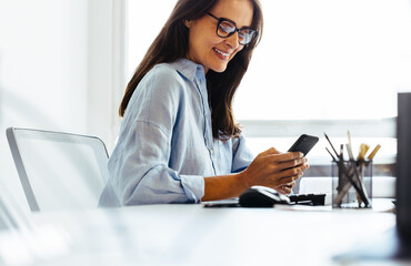 Design professional reading a text message on her phone in an office