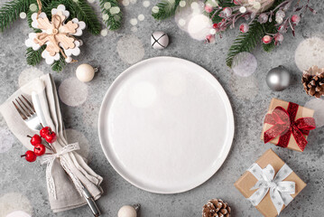 Christmas place setting and decorations on gray table.