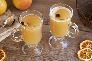 Hot pear drink with fresh pears and cinnamon on a table
