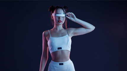 Woman in futuristic costume. Female in modern VR glasses interacting with network while having...