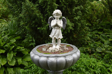 A wet statue of a little angel in the garden of a convent in the Russian city of Volkhov.
