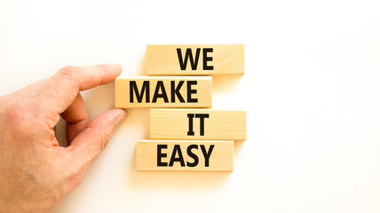 We make it easy symbol. Concept words We make it easy on wooden cubes. Beautiful white table white background. Businessman hand. Business motivational we make it easy concept. Copy space.