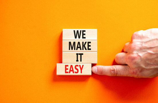 We make it easy symbol. Concept words We make it easy on wooden cubes. Beautiful orange table orange background. Businessman hand. Business motivational we make it easy concept. Copy space.