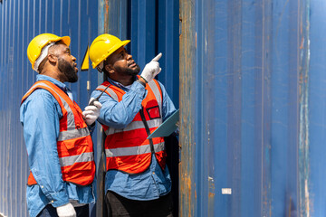 Two male engineers in a container shipping company Consulting to check the order for the container that is responsible