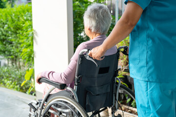 Fototapeta premium Caregiver help and care Asian senior or elderly old lady woman patient sitting in wheelchair on ramp at nursing hospital, healthy strong medical concept