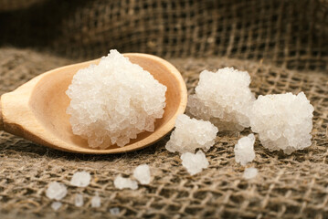 Sea salt lies on a cloth in a wooden spoon. Sea salt granules close up