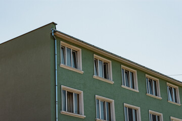 Green communist apartment building with a rainwater pipe on the corner