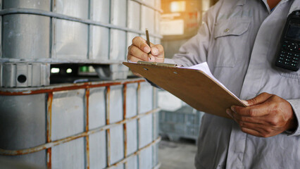 Quality inspectors are standing, check and record the quality and quantity of barrels chemical...