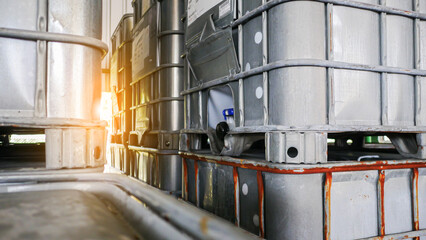 Chemicals drum, chemistry-related plastic containers, and metal-framed plastic barrels stock management in a warehouse for chemical storage. Concept of industrial manufacturing of chemicals and oil