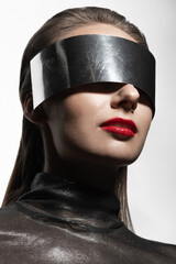 Fashion concept. Abstract woman studio portrait with make-up and big silver futuristic glasses or helmet covering her eyes. Model with red lipstick and wearing silver blouse in white studio background