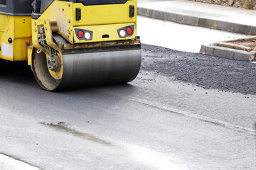 Road roller and asphalt paver machine at the construction site, with hot concrete and smoke