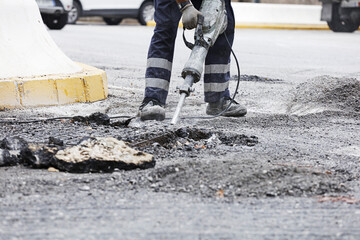 Operator with hammer, drills the pavement to install the new asphalt