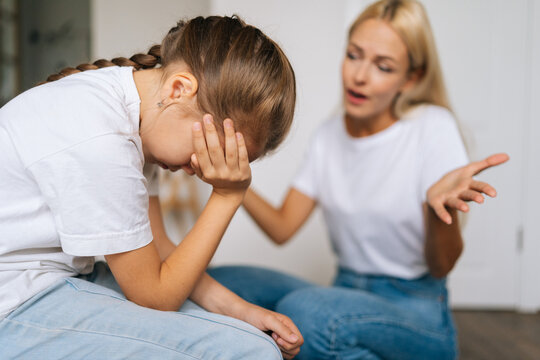 Close Up Side View Of Upset Cute Little Girl Crying Covering Face With Palm While Angry Mother Scolding, Raising Voice, Scream At Stubborn Difficult Little Child Daughter For Bad Behavior At Home.