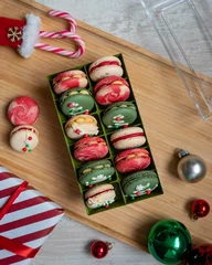 Fotobehang Vertical top view of colorful macarons in the box on a wooden surface - Christmas sweets © Pjm Captures/Wirestock Creators