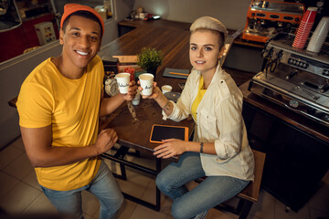 Baristas posing for the camera with caffeinated drinks in hands