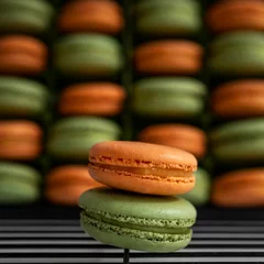 Zelfklevend Fotobehang Close-up view of orange and green sweet French macarons on the baking rack © Pjm Captures/Wirestock Creators