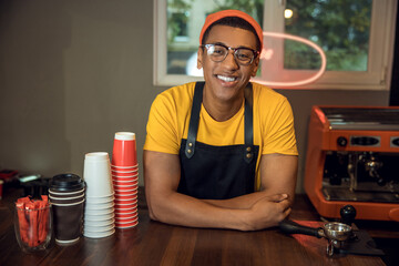 Smiling happy barista posing for the camera in his workplace