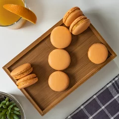Keuken foto achterwand Top view of orange-colored French macarons in a wooden box on a table © Pjm Captures/Wirestock Creators