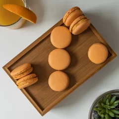 Foto op Canvas Top view of orange-colored French macarons in a wooden box on a table © Pjm Captures/Wirestock Creators