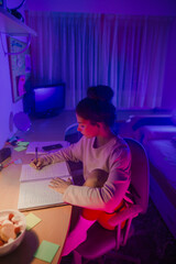 Girl studying in her room decorated with LED lights