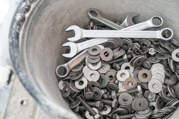 A bucket full of wrenches, washers and stud bolts is placed on the scaffolding.