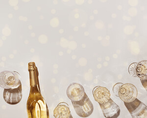 Flat lay with white sparkling wine bottle, set glasses wine with sunshine shadow and flare on light beige background. White wine aesthetic photo, copyspace. Summer holiday monochrome still life