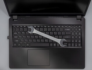 Stalowy klucz leżący na klawiaturze laptopa, naprawa komputera. - obrazy, fototapety, plakaty