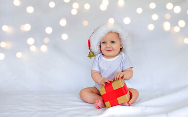 A boy in a red hat with a gift is sitting and smiling
