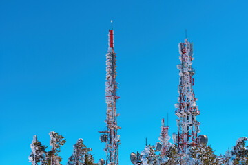 Communication tower antennas covered in snow with blue sky