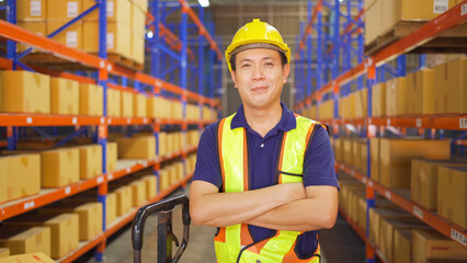 Portrait of Asian worker working in large warehouse retail store industry. Rack of stock storage....