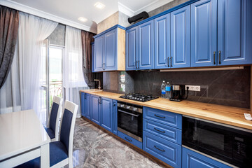 Modern kitchen in the Art Nouveau style. Wooden countertop and blue facade of kitchen furniture. Appliances.