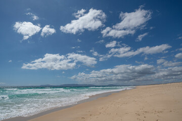 Fototapeta na wymiar Hot, sunny beach in summer in Portugal with blue sky, sea and waves.
