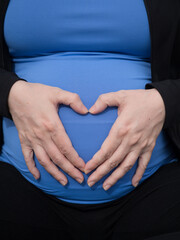 Unrecognizable pregnant woman forming a heart with her hands
