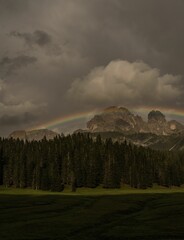 Landscape with a rainbow and gloomy clouds over Dolomite mountains, Italy