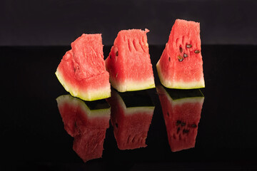 Delicious watermelon slices on black reflective surface