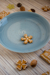 Painted traditional Christmas gingerbreads arranged on blue plate on white wooden table, various xmas shapes