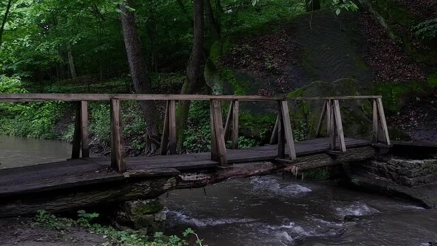 An ancient wooden bridge over a mountain river in the forest, the sound of water and the singing of birds