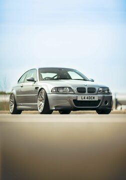 Vertical shot of grey modern BMW M3 CSL on the road with blue sky in the background