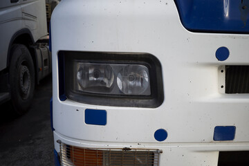 Fragment of the cab of heavy truck. Truck parts - headlight, radiator grill, bumper,
