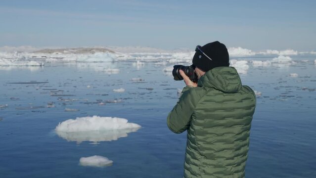 Medium Shot Of A Man Taking Pictures Of Floating Icebergs On The Sea