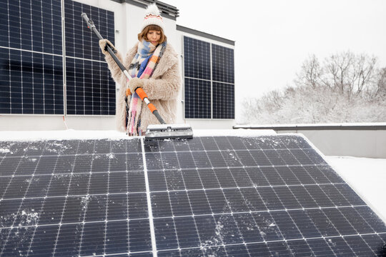 Woman cleans solar panels from snow